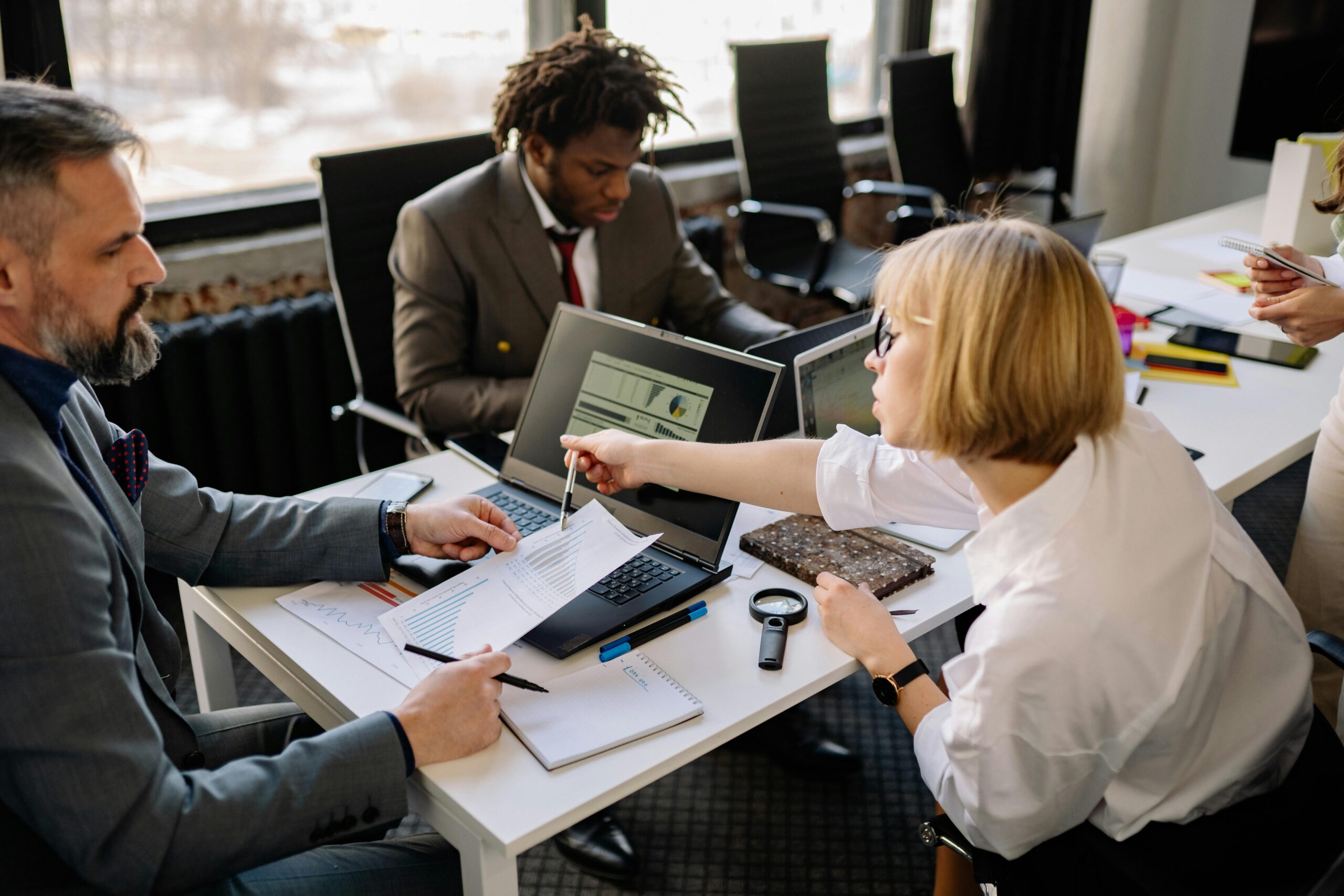 Business team of three discussing project plans in a modern office setting.